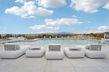 A pool surrounded by white lounge chairs.at The Garrison Luxury Apartment Homes, Fountain, CO 80817